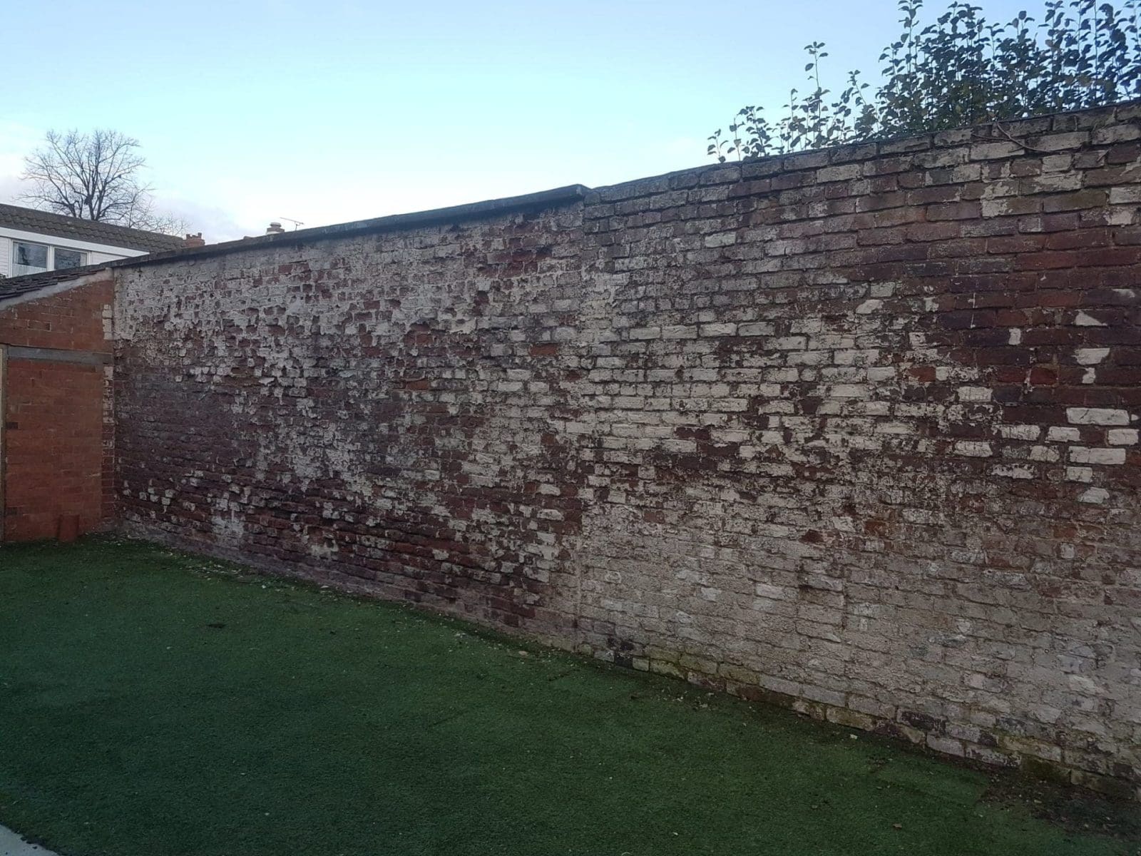 brick garden wall before a long day removing paint with sand jet