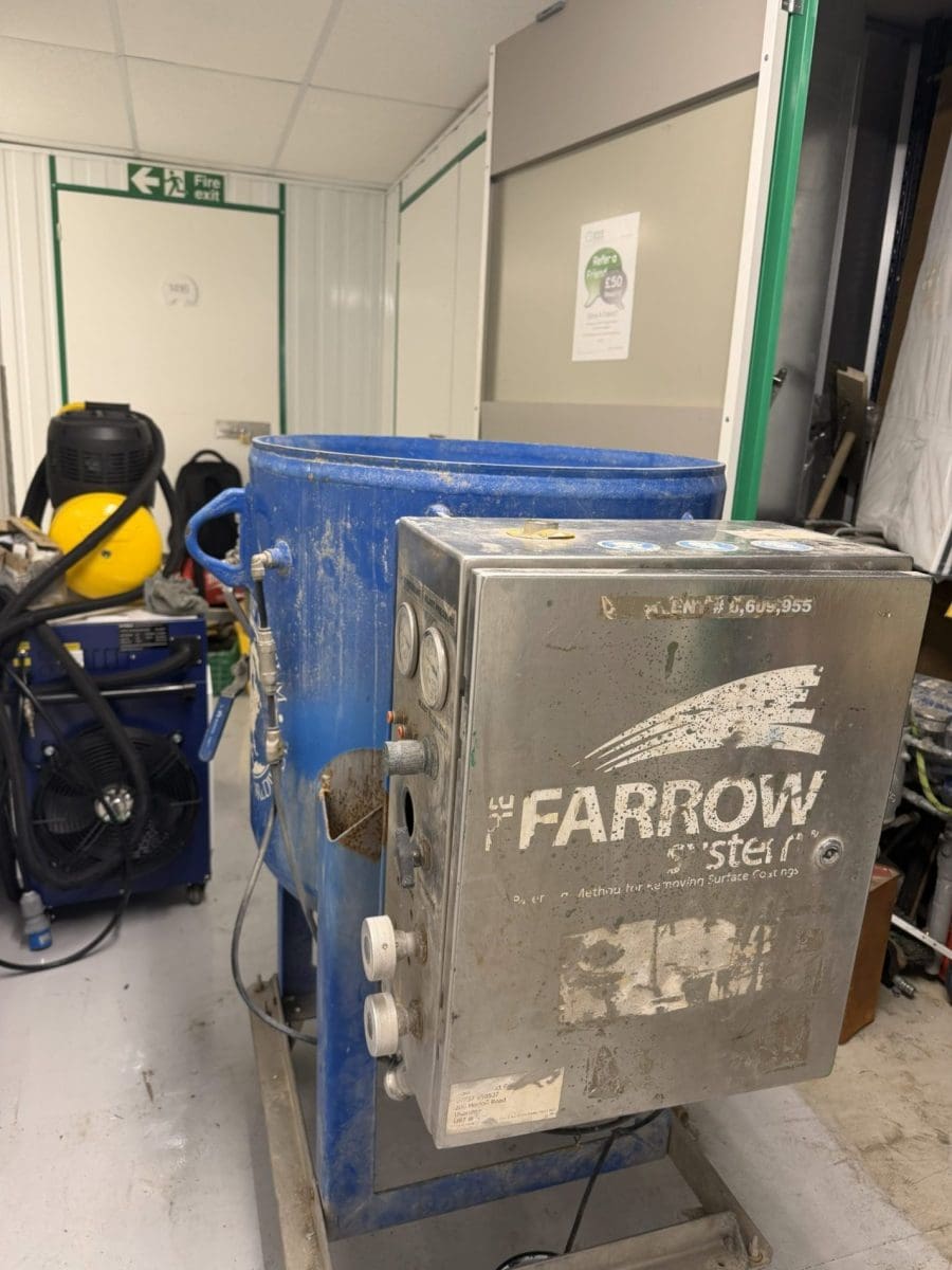 The Farrow System wet blasting machine with blue hopper in workshop setting
